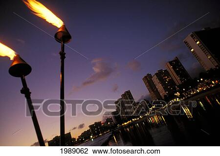 Stock Image - Hawaii, Oahu, Waikiki Lights At Night With Tiki Torches.. Fotosearch