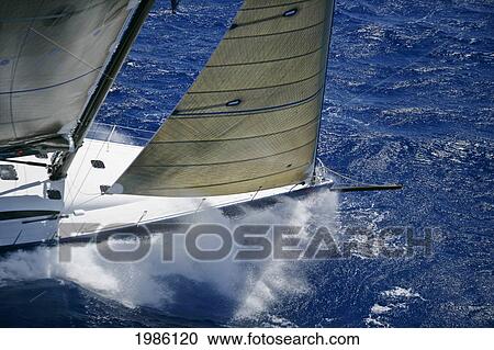 Stock Image - Hawaii, Oahu, Waikiki Offshore Series 2005, Sailboat On Blue Ocean, Front Of Boat Splashing Along The Water.. Fotosearch