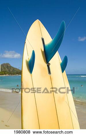 Stock Photo - Hawaii, Oahu, Waikiki, Surfboard Stuck Into The Sand At The Waters Edge With Diamond Head In Background.. Fotosearch