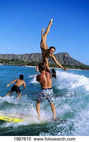 Hawaii, Oahu, Waikiki, Tandem Surfing, Man Holds Woman In An Elaborate Pose While Surfing. No Model Release View Large Photo Image Stock Image - Hawaii, Oahu, Waikiki, Tandem Surfing, Man Holds Woman In An Elaborate Pose While Surfing. No Model Release. Fotosearch