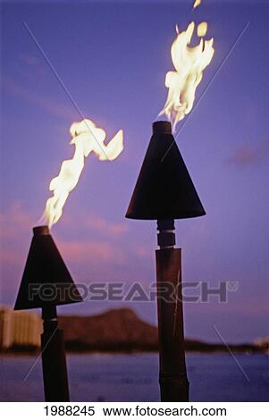 Stock Photography - Hawaii, Oahu, Waikiki, Tiki Torches Burn At Sunset With Diamond Head In Background. Fotosearch