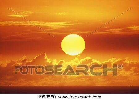 Stock Image - Hawaii, Oahu, Waikiki, View Of Huge Orange Sun Sinking Towards The Horizon.. Fotosearch