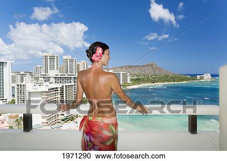 Stock Image - Hawaii, Oahu, Waikiki, Woman On Hotel Balcony Overlooking Waikiki Beach And Diamond Head, View From Behind.. Fotosearch