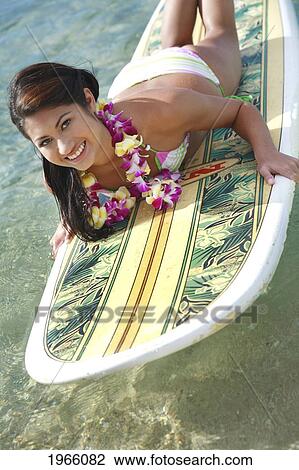 Stock Image - Hawaii, Oahu, Waikiki, Young Woman Laying On Surfboard In Water.. Fotosearch