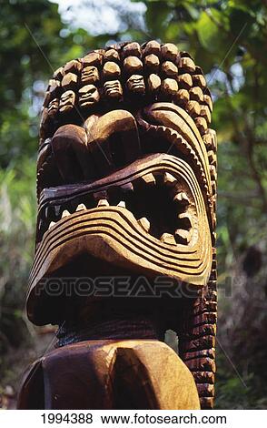 Stock Photo - Hawaii, Oahu, Waimea Valley, Closeup Of Wooden Tiki Statue, Greenery In Background. Fotosearch