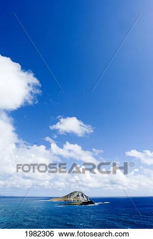 Stock Photograph - Hawaii, Oahu, Windward, Waimanalo, Rabbit Island, calm blue ocean, cloudy blue sky. Fotosearch
