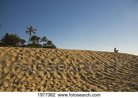 Stock Image - Hawaii, Oahu, Woman Sitting On Beach On North Shore.. Fotosearch