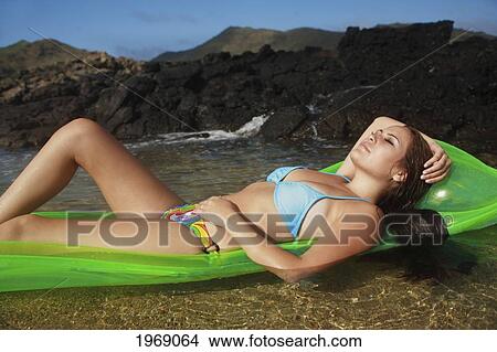 Picture - Hawaii, Oahu, Young Beautiful Female Relaxing On A Bright Beach Floater In The Water. Fotosearch