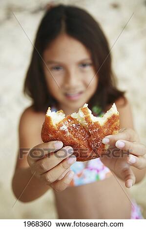 Stock Image - Hawaii, Oahu, Young Girl Enjoying A Malasada.. Fotosearch