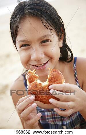 Stock Image - Hawaii, Oahu, Young Girl Enjoying A Malasada.. Fotosearch