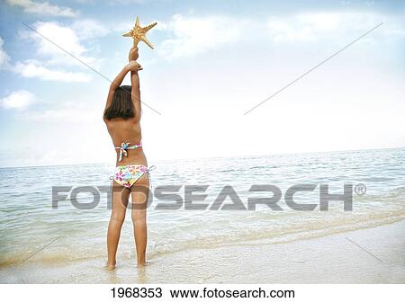 Stock Image - Hawaii, Oahu, Young Girl Holding A Starfish, View From Behind.. Fotosearch