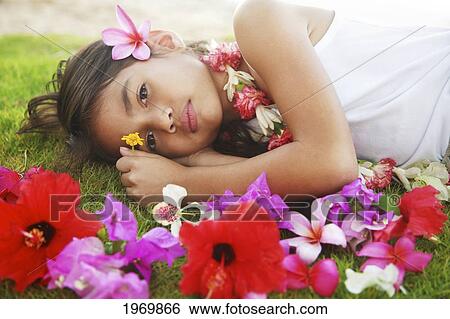 Stock Photograph - Hawaii, Oahu, Young Girl Laying On The Grass Next To A Bunch Of Colorful Flowers.. Fotosearch