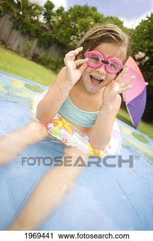 Stock Image - Hawaii, Oahu, Young Girl Playing In A Pool With An Innertube And Goggles.. Fotosearch