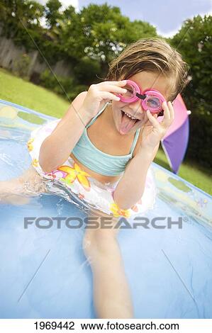 Stock Image - Hawaii, Oahu, Young Girl Playing In A Pool With An Innertube And Goggles.. Fotosearch