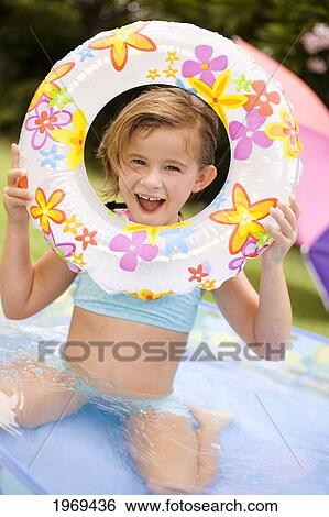 Stock Photograph - Hawaii, Oahu, Young Girl Playing In A Pool With An Innertube.. Fotosearch