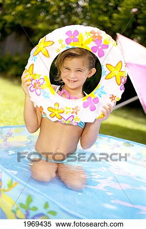 Stock Photography - Hawaii, Oahu, Young Girl Playing In A Pool With An Innertube.. Fotosearch