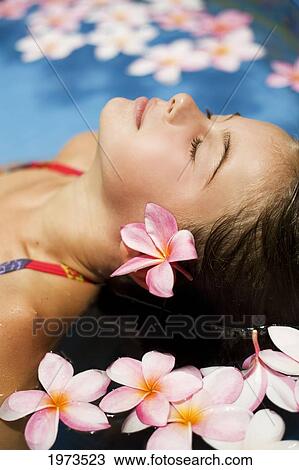 Stock Image - Hawaii, Oahu, Young Girl Resting In A Pool With Plumerias.. Fotosearch