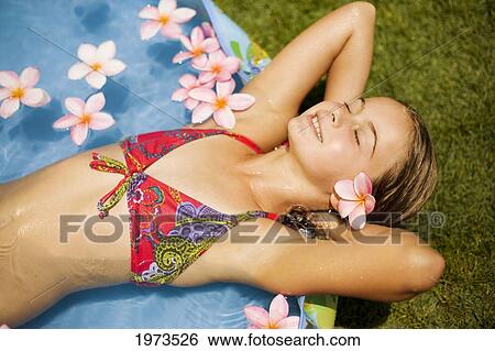 Stock Photograph - Hawaii, Oahu, Young Girl Resting In A Pool With Plumerias.. Fotosearch