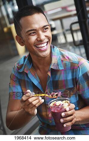 Picture - Hawaii, Oahu, Young Local Man Eating And Enjoying A Delicious Acai Cup.. Fotosearch