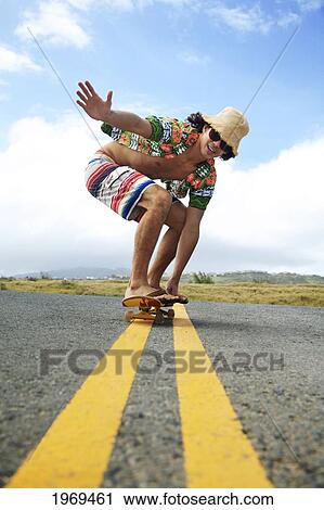 Stock Image - Hawaii, Oahu, Young Male Riding A Skateboard On The Roadway.. Fotosearch