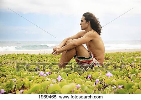 Stock Photography - Hawaii, Oahu, Young Male Sitting Down On The Beach In Deep Thought.. Fotosearch