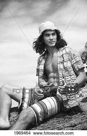 Hawaii, Oahu, Young Male With Vintage Aloha Shirt And Straw Hat Relaxing Holding A Ukulele. View Large Photo Image Picture - Hawaii, Oahu, Young Male With Vintage Aloha Shirt And Straw Hat Relaxing Holding A Ukulele.. Fotosearch