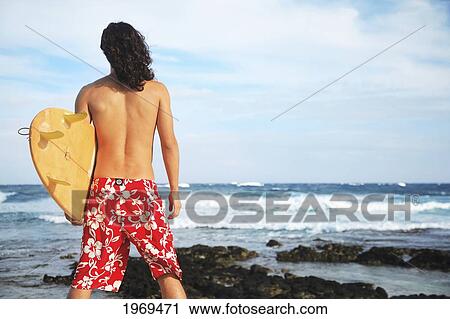 Stock Image - Hawaii, Oahu, Young Man At The Beach With Surfboard.. Fotosearch