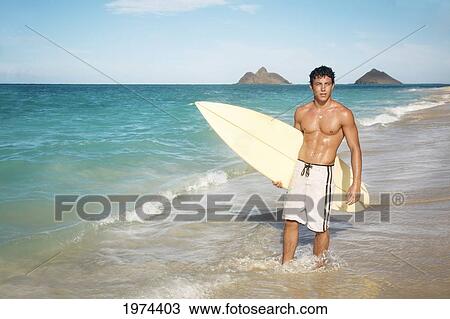 Stock Image - Hawaii, Oahu, Young Man At The Beach With Surfboard.. Fotosearch