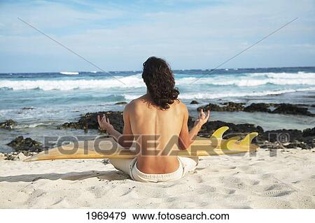 Stock Photo - Hawaii, Oahu, Young Man At The Beach Meditating With Surfboard.. Fotosearch