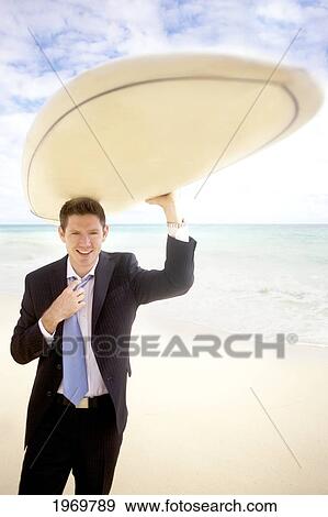 Stock Photo - Hawaii, Oahu, Young Man At The Beach With Surfboard In Business Attire.. Fotosearch