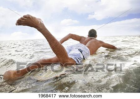 Hawaii, Oahu, Young Man Paddling On His Surfboard In The Water. View Large Photo Image Stock Photo - Hawaii, Oahu, Young Man Paddling On His Surfboard In The Water.. Fotosearch