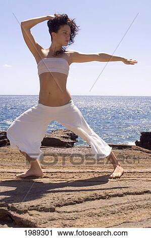 Stock Image - Hawaii, Oahu, Young Woman Doing Yoga Next To The Ocean.. Fotosearch