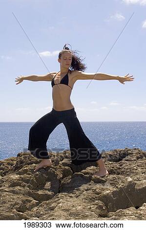 Stock Image - Hawaii, Oahu, Young Woman Doing Yoga Next To The Ocean.. Fotosearch