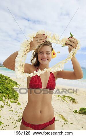 Stock Photograph - Hawaii, Oahu, Young Woman Offers Lei On Beach.. Fotosearch