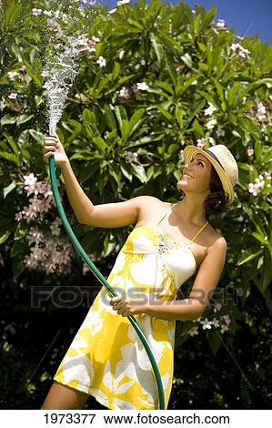 Stock Photo - Hawaii, Oahu, Young Woman Splashing Water On Herself With Hose.. Fotosearch