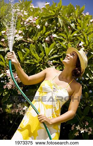 Stock Photography - Hawaii, Oahu, Young Woman Splashing Water On Herself With Hose.. Fotosearch