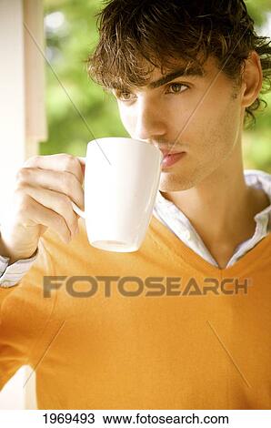 Stock Image - Hawaii, Portrait Of A European Male Model In Orange Sweater Drinking Coffee.. Fotosearch