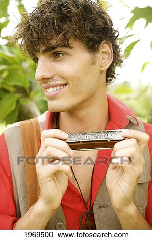 Stock Image - Hawaii, Portrait Of A European Male Model Playing A Harmonica.. Fotosearch