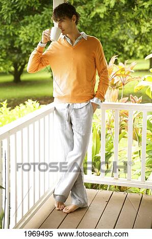 Stock Photography - Hawaii, Portrait Of A European Male Model In Orange Sweater Drinking Coffee.. Fotosearch