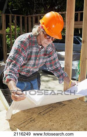 Stock Photo - Hawaii, Senior male construction worker reading blueprints at a construction site.. Fotosearch