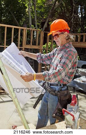 Hawaii, Senior male construction worker reading blueprints at a construction site. View Large Photo Image Stock Photograph - Hawaii, Senior male construction worker reading blueprints at a construction site.. Fotosearch