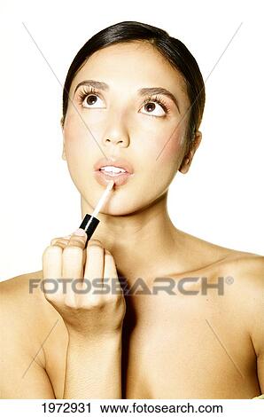 Stock Image - Hawaii, Studio Headshot Of A Beautiful Girl Putting On Lipstick.. Fotosearch