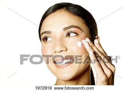 Stock Photo - Hawaii, Studio Headshot Of A Beautiful Girl Applying Moisturizer On Her Skin.. Fotosearch