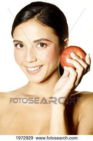 Stock Photo - Hawaii, Studio Headshot Of A Beautiful Girl Holding An Apple.. Fotosearch