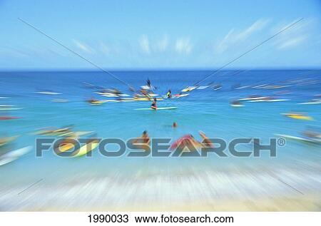 Stock Image - Hawaii, Surfers Paddling Out In Beautiful Water, Blurred Action. Fotosearch