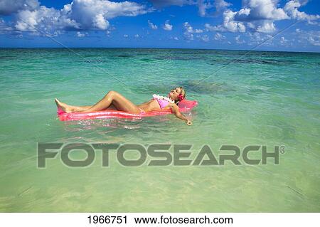 Stock Image - Hawaii, Teenage Girl In Ocean With Inflatable.. Fotosearch