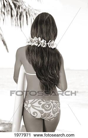 Stock Image - Hawaii, Teenage Surfer Girl From Behind, Wearing A Plumeria Lei And Holding Surfboard (Sepia Photograph).. Fotosearch