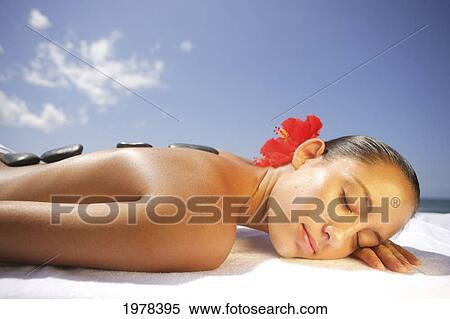 Stock Photography - Hawaii, Topless Girl With Stones Laid Upon Her Back, Laying Down To Receive Massage.. Fotosearch