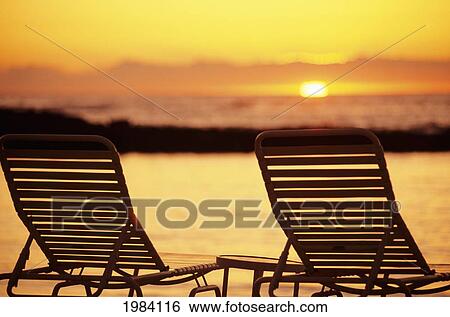 Stock Photograph - Hawaii, Two Silhouetted Chairs On Beach At Sunset, View From Behind.. Fotosearch