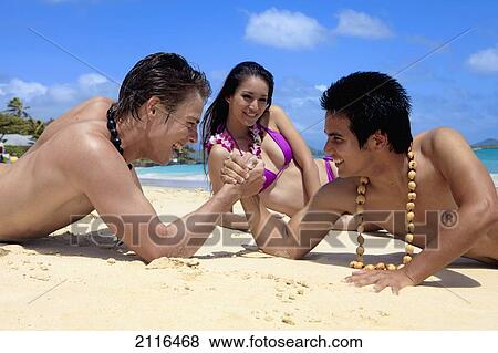 Hawaii, Two young men arm wrestling on the beach while girl watches. View Large Photo Image Stock Photo - Hawaii, Two young men arm wrestling on the beach while girl watches.. Fotosearch